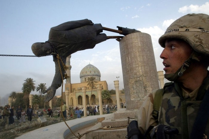 U.S. Marine Kirk Dalrymple watches as a statue of Iraq's President Saddam Hussein falls in central Baghdad. [2003] Source: Reuters