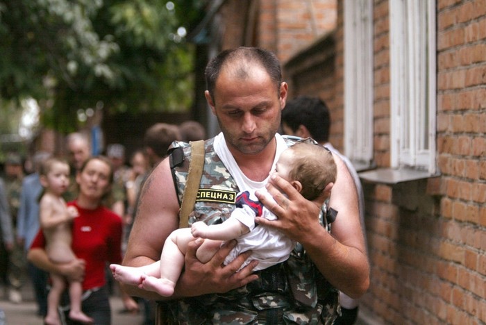 A Russian police officer carries a released baby from the school seized by heavily armed masked men and women in the town of Beslan. [2004] Source: Victor Korotayev