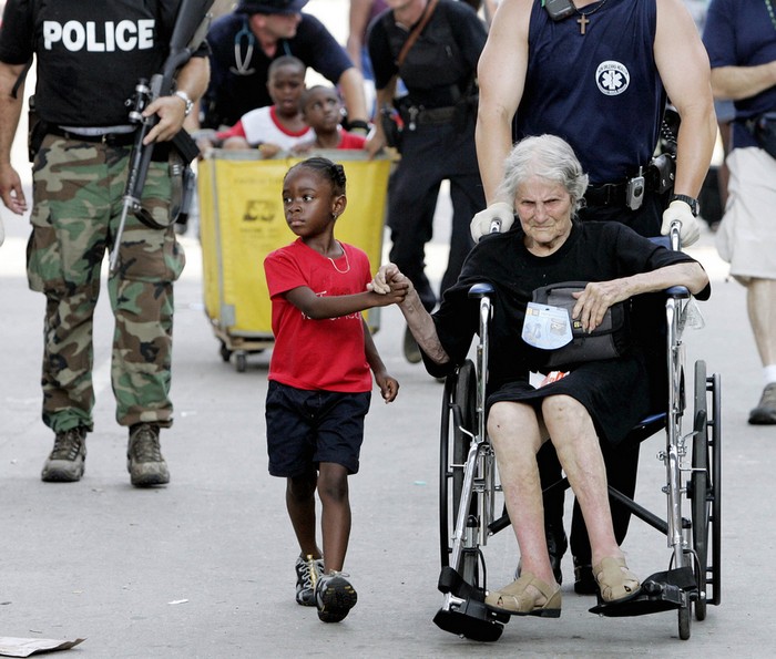 Tanisha Blevin, 5, holds the hand of fellow Hurricane Katrina victim Nita LaGarde, 105, as they are evacuated from the convention center in New Orleans. [2005] Source: Eric Gay