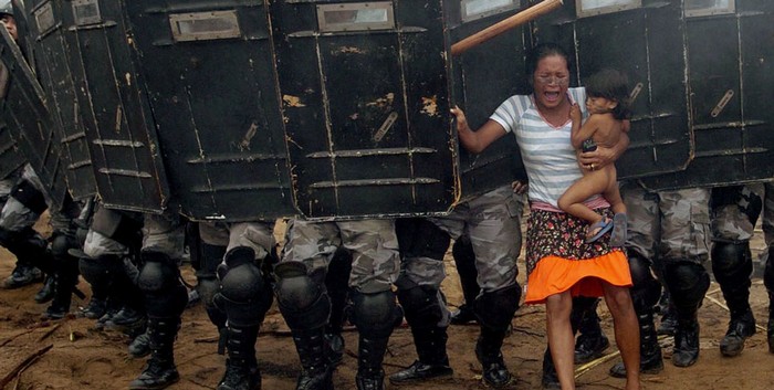  An indigenous woman holds her child while trying to resist the advance of Amazonas state policemen in Manaus who have been sent to evict natives. [2008] Source: Luiz Vasconcelos