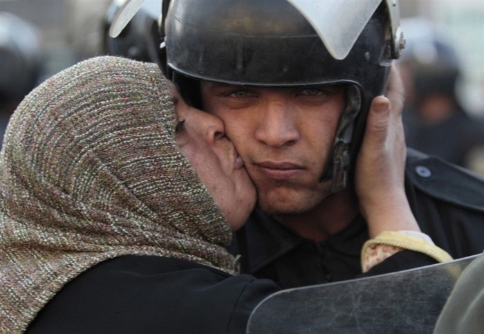  An Egyptian woman kisses a policeman, who had refused to fire on protestors, during the revolution against the Mubarak Government [2011] Source: Unknown Photographer