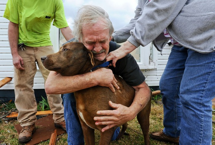  Greg Cook hugs his dog Coco after finding her inside his destroyed home in Alabama following the Tornado. [2012] Source: The Decatur Daily