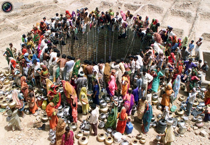People gather water from a huge well in the village of Natwarghad in the western Indian state of Gujarat. More than 1 billion people still lack access to clean drinking water. [2003] Source: Amit Dave